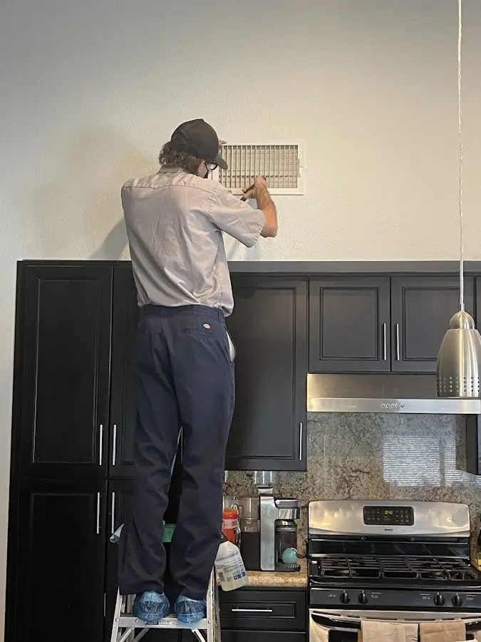 Technician inspecting an air vent during HVAC service in Rathdrum